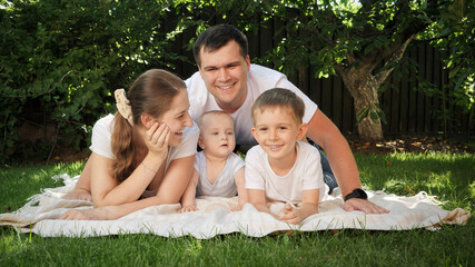 Portrait of happy smiling family relaxing and having good time together on grass at park