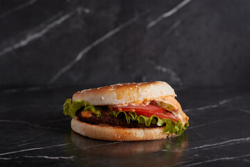burger with meat and cheese on the table, american cuisine, close-up, tomato, dark background, marble,