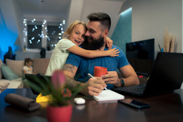 Young businessman working at home while using laptop and his daughter interrupts him