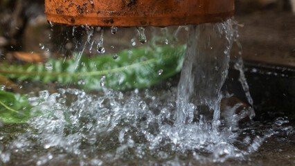 Close-up view of raindrops flowing down from the pipeline. A stream of water flows from the roof...