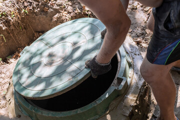 The man opens the sewer hatch. Installation and maintenance of septic tanks