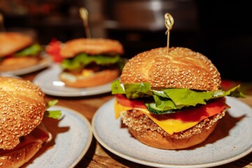 cheeseburgers and fries on table top with onion, tomato, lettuce and cheese