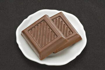 Chocolate em cima de um prato branco no fundo escuro
