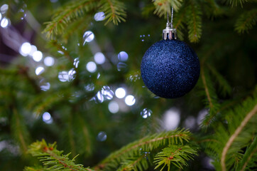 Ball is a decoration for a Christmas tree on a branch with bokeh glitters