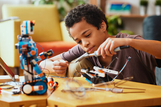 Smart African boy making a robot at home for science class. Robotics and education.