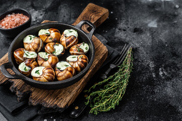 Delicatessen food - Bourgogne Escargot Snails with garlic butter in a pan. Black background. Top view. Copy space
