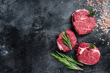 Fillet Mignon tenderloin raw meat beef steaks on butchery table. Black background. Top view. Copy...