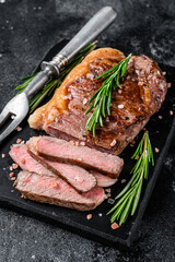 Fototapeta na wymiar Cut roasted new york strip beef meat steak or striploin on a marble board. Black background. Top view