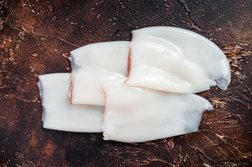 Raw Squid or Calamari tubes on a kitchen table. Dark background. Top view