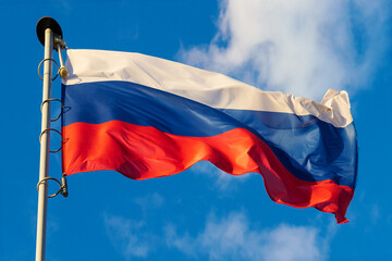 Fototapeta na wymiar Fluttering flag of Russia on a flagpole against bright blue sky background