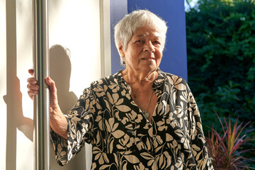 Portrait of mature woman standing in front house.