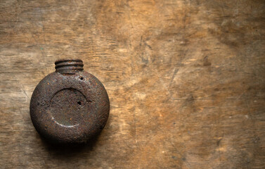 Naklejka na ściany i meble Rusty military oil can on a wooden background.Metal oilcan hunter with rust and holes.