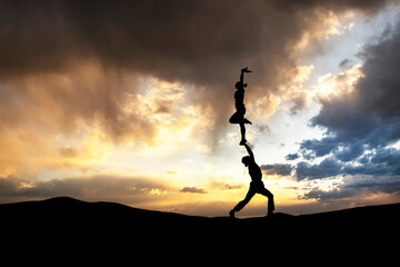 The couple of acrobats perform a beautiful dance at sunset