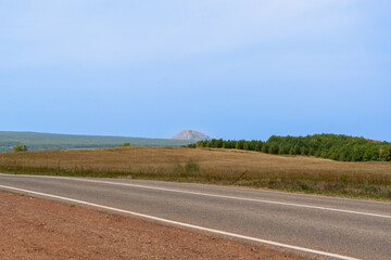 Fototapeta premium The road, the forest and the mountain is visible in the distance.