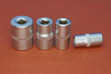four gray metal tool heads on a brown table