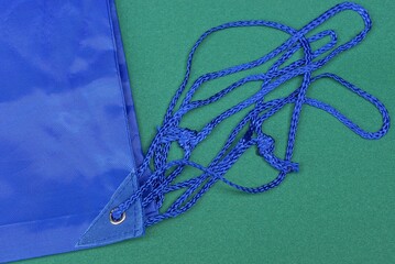 blue rope lace in a gray metal ring on a  backpack fabric on a green table