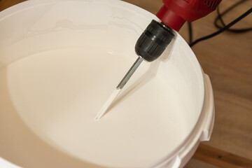 Mixing paint (plaster) in a bucket with a mixer (drill).