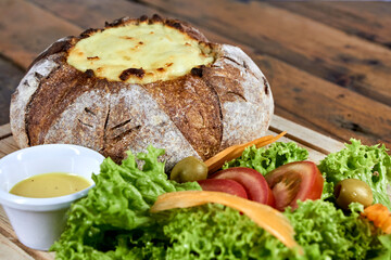 peasant bread stuffed with meat and chicken covered with cheese with salad