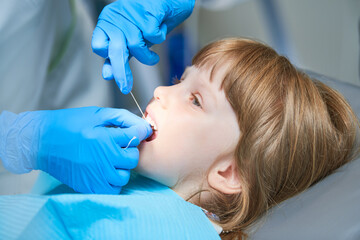 Children dentistry. Liitle girl an dentist examination, teeth cleaning and treatment.