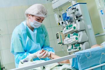 doctor examining newborn baby in incubator at neonatal resuscitation center