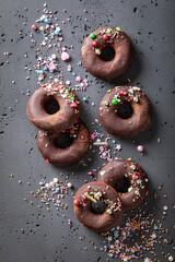 Dark brownie donuts made of chocolate and sprinkles.