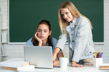 Students girls friends in classroom at school college or university. Two students doing homework together and helping each other.