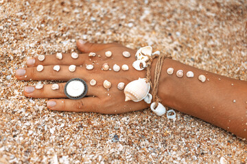close up of woman hand with accessories lying on the sand