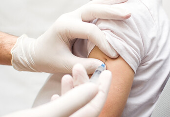 Vaccination, immunization, disease prevention concept. A child or teenager receives the Covid-19 or flu vaccine in a hospital. Professional nurse or doctor giving an antiviral injection to a patient