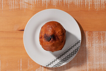 Top view of 80 grams panettone on a white plate on a wooden table.