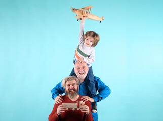 Three different generations ages grandfather father and child son playing with toy plane in studio. Isolated background.