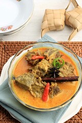Gulai Sapi is Beef Curry Typically Traditional Food from Padang, West Sumatera, Indonesia. Served at the Table with Bowl and Ketupat Lebaran. Menu for Eid al Adha (Idul Adha)