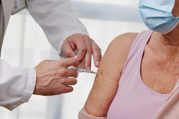 Elderly woman receiving vaccine. Medical worker vaccinating senior patient against coronavirus, influenza, flu or pneumonia