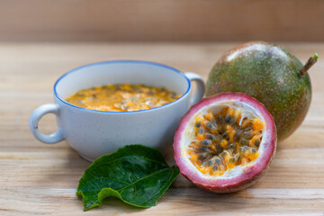 Half of the passion fruit (maracuya) with fruit pulp and passion fruit seeds in a bowl on  wooden table, Passion fruit, a fruit that is sour and high in vitamins.