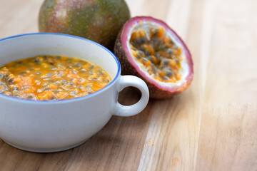 Half of the passion fruit (maracuya) with fruit pulp and passion fruit seeds in a bowl on  wooden table, Passion fruit, a fruit that is sour and high in vitamins.