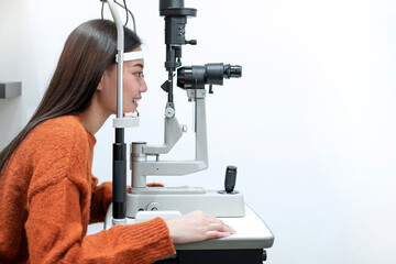 Asian beautiful woman doing eye test with slit lamp in modern ophthalmology clinic, side view,...