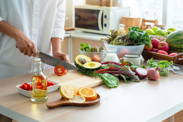 Closeup of hand slicing fresh tomato,  woman preparing tomato for salad in her kitchen