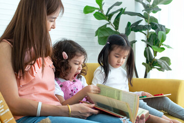 lovely family, mother and two daughters reading a book on couch, little girl felt sleepy and yawned