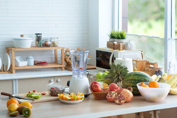 Modern kitchen with fruits and vegetables on wooden table, green tree outside the window