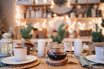 a teapot on the table in decorated kitchen for new year. electric garlands.