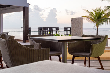 tables et chaises sur un sol en bois avec vue sur la mer lors d'un lever de soleil