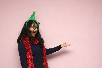 Young Latina teenager with Christmas hat and glasses shows her enthusiasm for the arrival of December and celebrating Christmas
