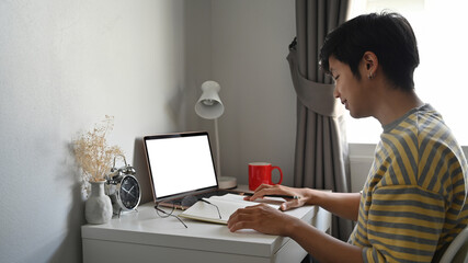 Side view asian man sitting in comfortable home and using laptop computer.