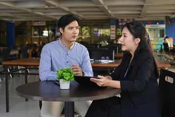 Beautiful businesswoman holding digital table and explaining information to her colleagues.