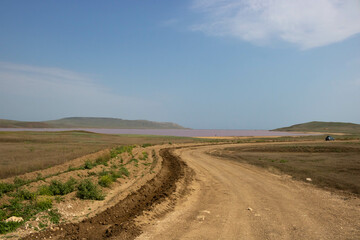 Fototapeta na wymiar An empty dirt road near the pink lake on a summer day