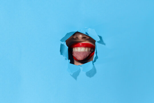 woman peeping through the holes in the poster blue studio background