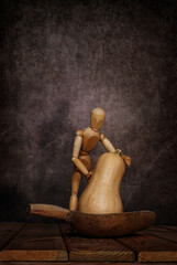 A wooden emotional gestalt man with a pumpkin and a scoop on a wooden table and an artistic...
