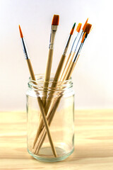 brushes for drawing of various diameters in a glass jar on a white background