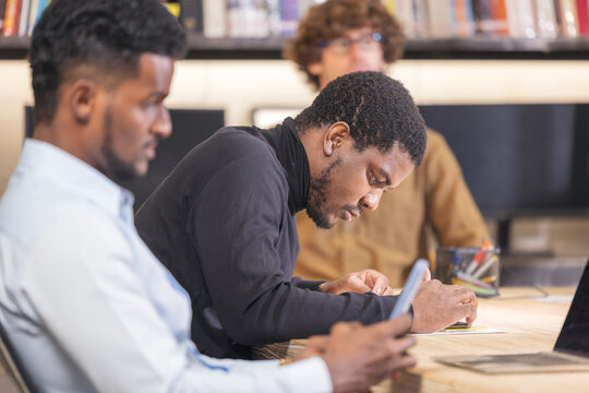 Portrait Of A Happy Caucasian Male Employee Posing For A Corporate Business Catalog With Coworkers In The Backdrop During A Photo Shoot In The Office.