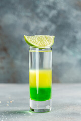 Mexican alcoholic cocktail drinks shot. made of Absinthe, Lemon Fresh, Grenadine. green alcoholic cocktail with lime