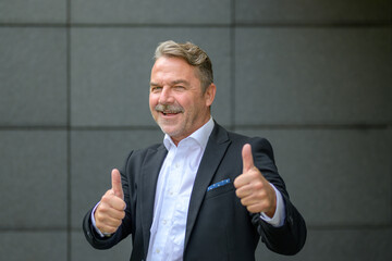 Portrait of an elegant and successful businessman showing thumbs up